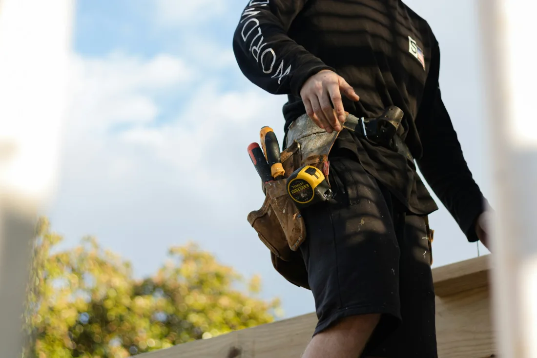 A craftsperson holding work boots while preparing timber.